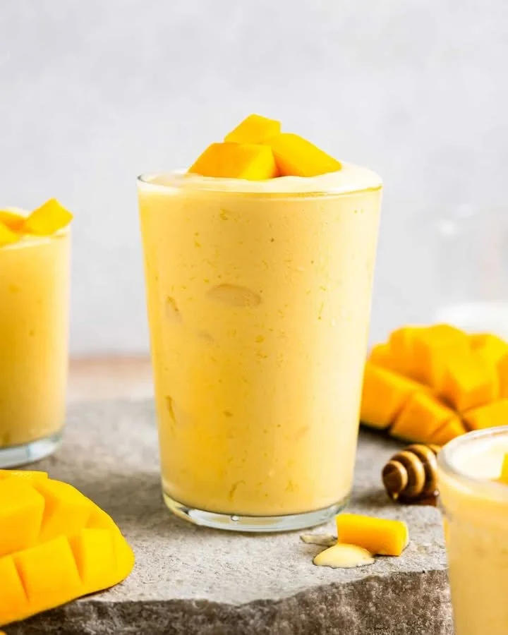 Delicious mango smoothie in a glass with fresh mango slices