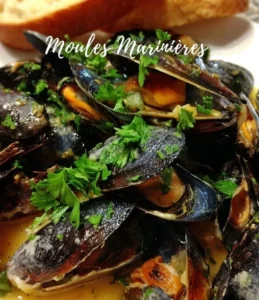 Delicious Marinere Mussels served on a plate with herbs and lemon wedges.