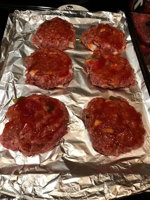 Tasty meatloaf patties served on a plate with fresh herbs