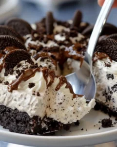 Creamy no-bake Oreo cheesecake topped with crushed Oreos and chocolate drizzle