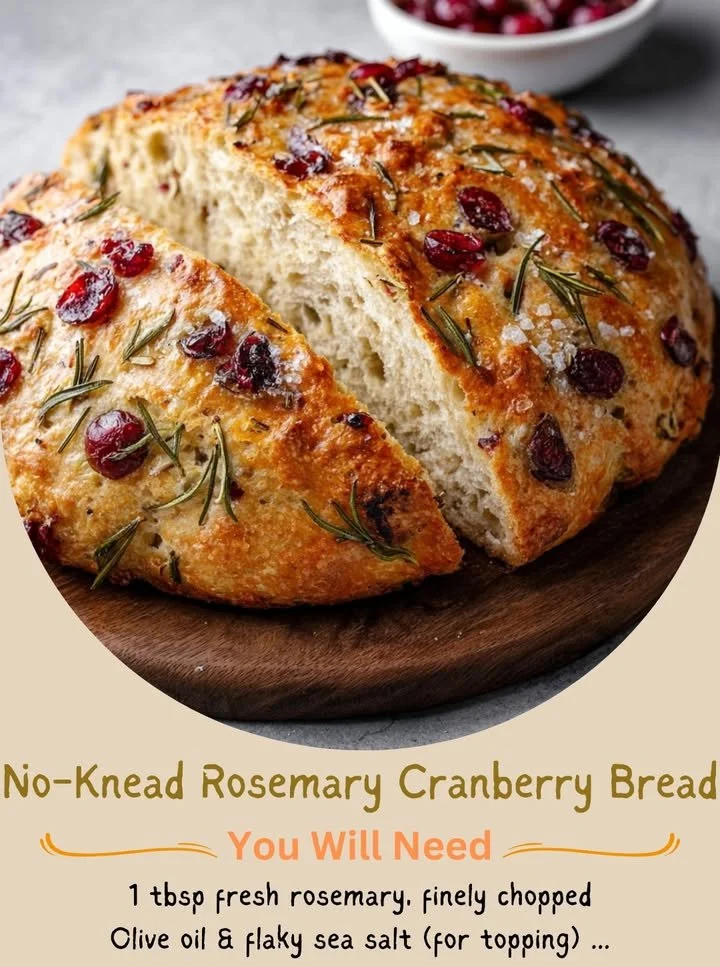 Loaf of no-knead rosemary cranberry bread freshly baked on a wooden board.