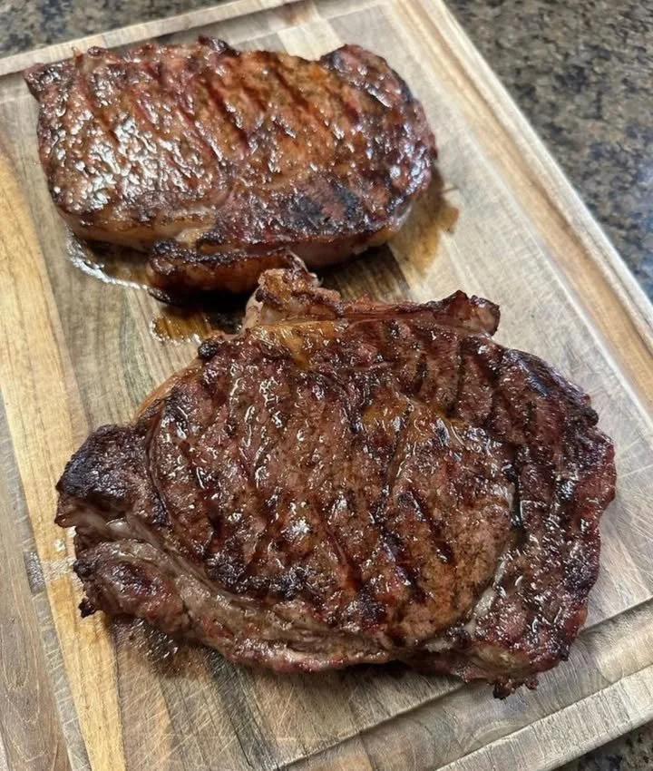 A perfectly cooked steak on a plate, garnished with herbs and spices.