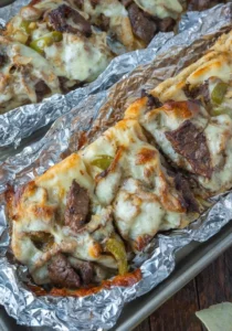 Philly cheesesteak French bread pizza topped with sautéed onions and cheese