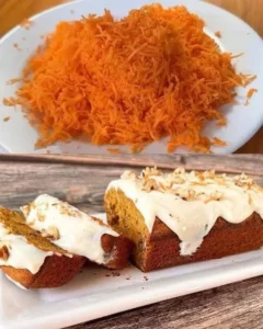 Slice of homemade carrot walnut cake with frosting on a plate