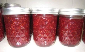 Jar of quick and easy strawberry jam with fresh strawberries and spreader