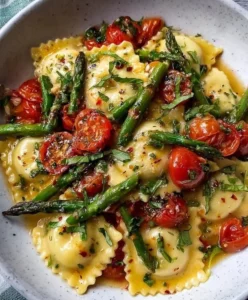 Delicious ravioli with tomatoes, asparagus, garlic, and herbs served in a bowl.