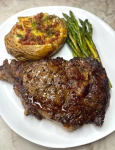 Ribeye steak with baked potato and asparagus on a plate
