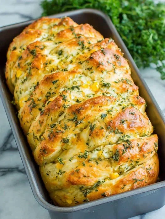 Loaf of rustic no-knead rosemary garlic bread garnished with herbs