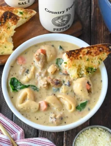 Bowl of Sausage Tortellini Soup garnished with herbs