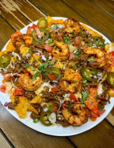 Shrimp and beef loaded nachos topped with cheese, guacamole, and jalapeños.