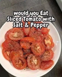 Fresh sliced tomato seasoned with salt and pepper on a plate