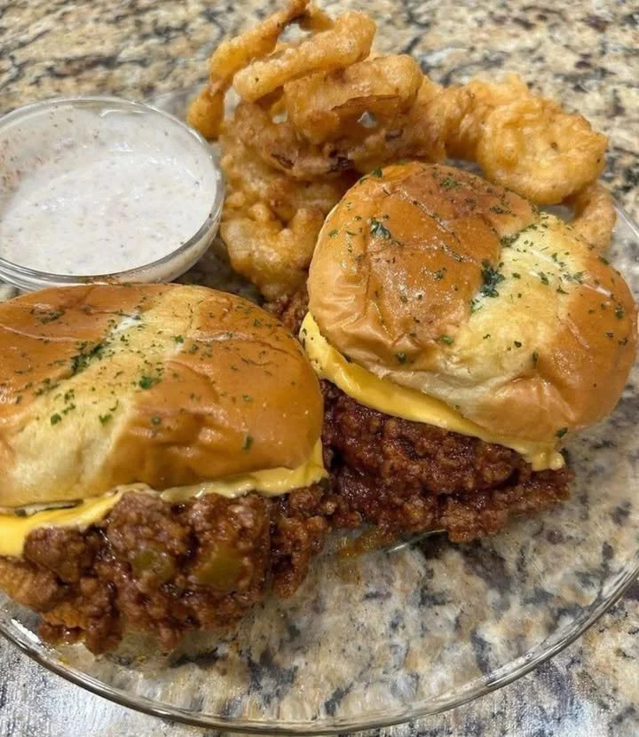 Delicious homemade Sloppy Joe sandwich with a side of pickles.
