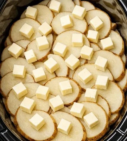 Slow cooker cheesy potatoes topped with cheese and herbs