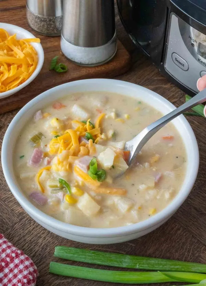 Bowl of slow cooker ham and potato soup garnished with herbs
