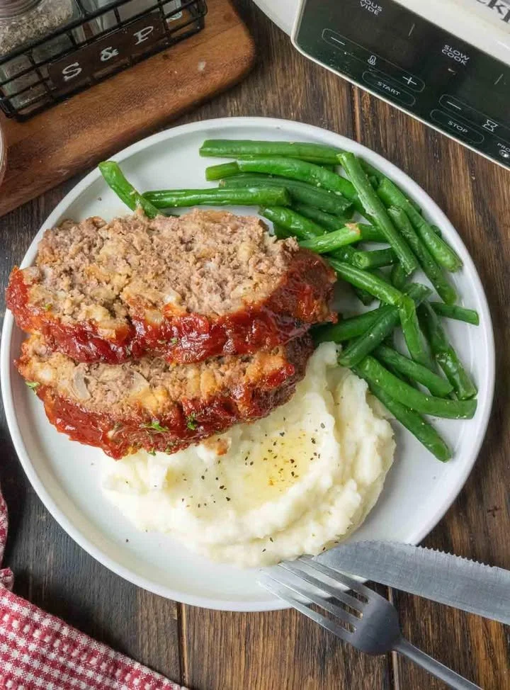 Delicious slow cooker meatloaf served with mashed potatoes and gravy.