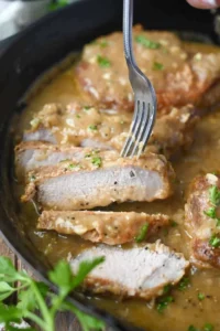 Delicious smothered pork chops served with creamy gravy and herbs