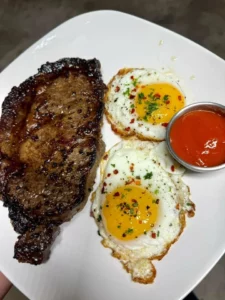 Delicious plate of steak and eggs served with garnishes for breakfast