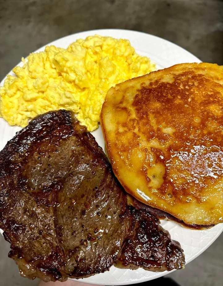 Delicious steak, scrambled eggs, and pancakes served on a plate