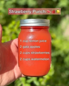 Delicious strawberry punch drink in a glass with fresh strawberries and ice.