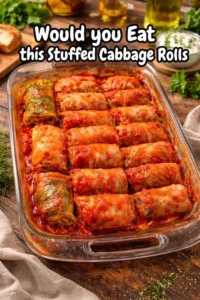 Plate of stuffed cabbage rolls filled with rice and meat, topped with tomato sauce.