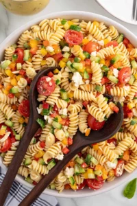 Colorful summer pasta salad featuring fresh vegetables and dressing.