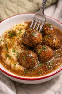 Plate of Swedish meatballs with mashed potatoes and gravy, garnished