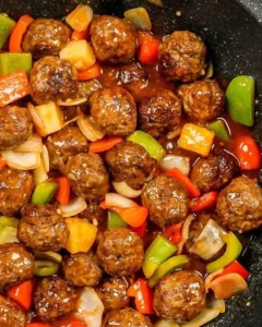 Plate of sweet and sour meatballs garnished with herbs