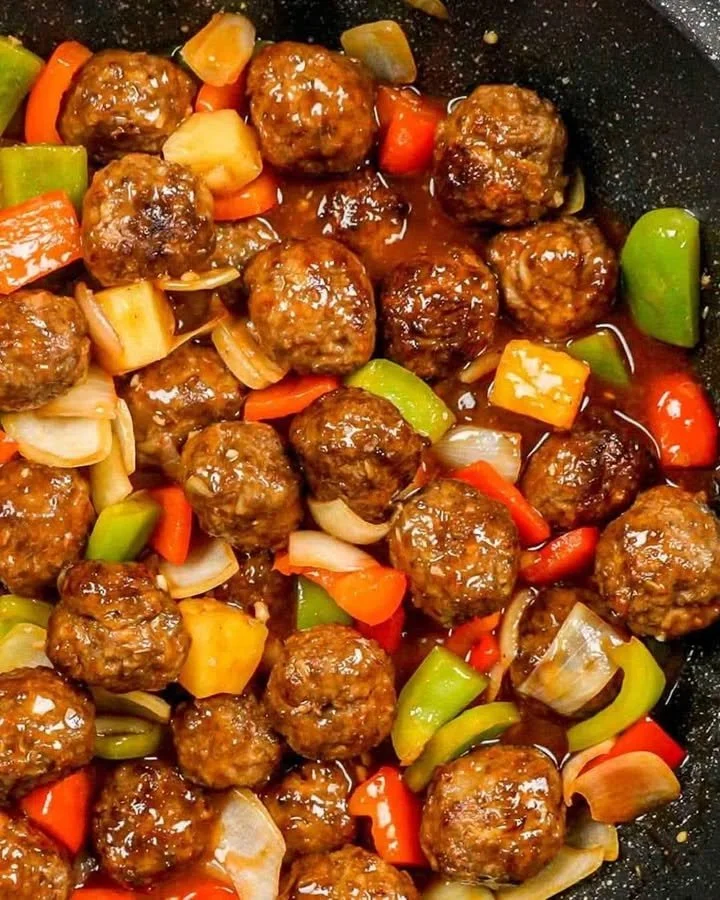 Plate of sweet and sour meatballs garnished with herbs
