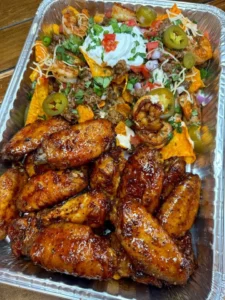 Plate of Sweet Chili Jerk Wings served with beef and shrimp loaded nachos