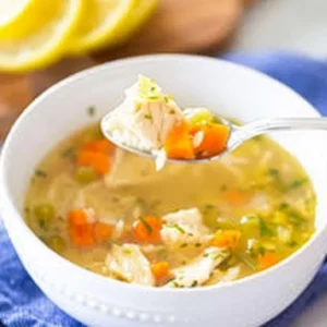 Bowl of healing chicken soup with vegetables and herbs, perfect for comfort food
