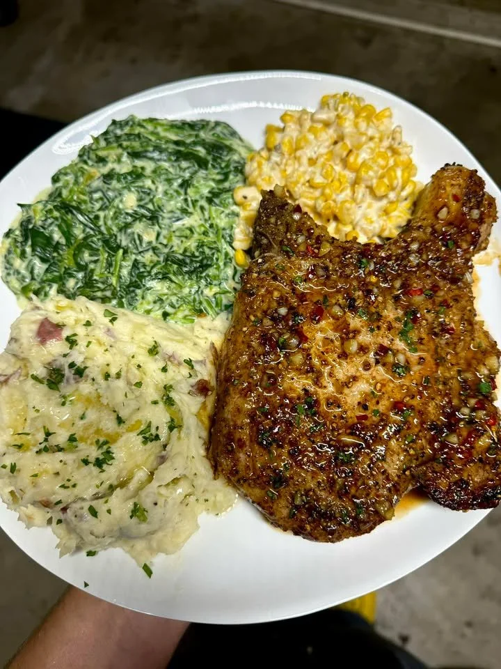 Thick cut pork chop with creamed corn and spinach on a plate