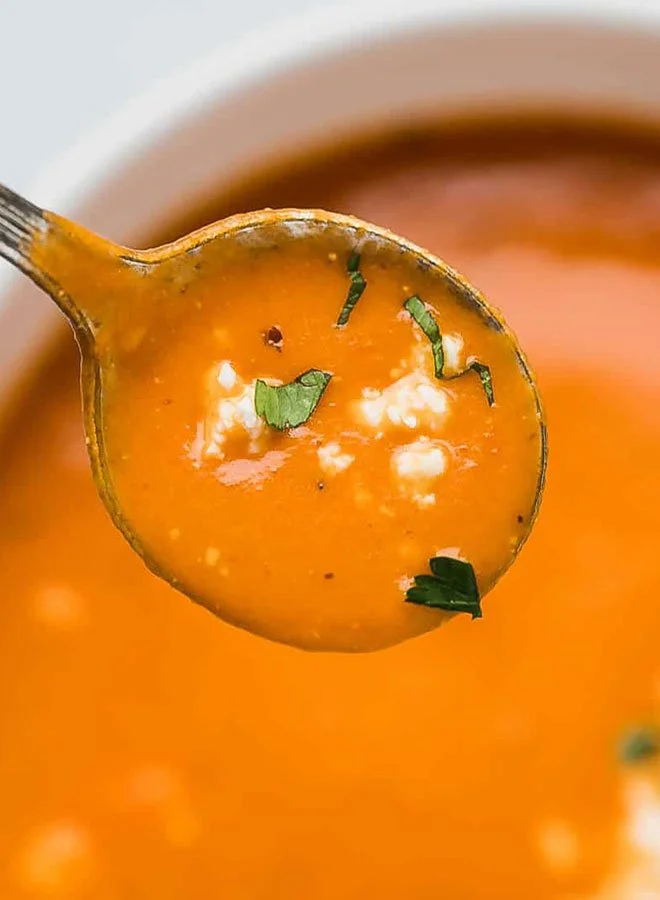 Bowl of rich Tomato Feta Soup garnished with fresh herbs