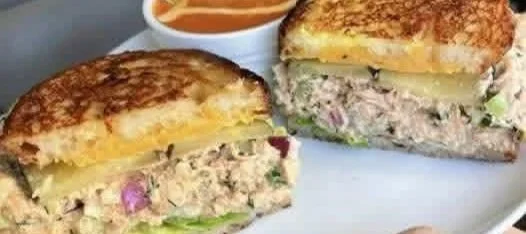 A tasty tuna salad sandwich with fresh ingredients and a side of greens
