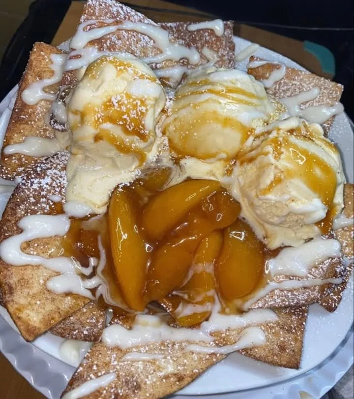 Warm peach cobbler topped with a golden crust served in a rustic dish.