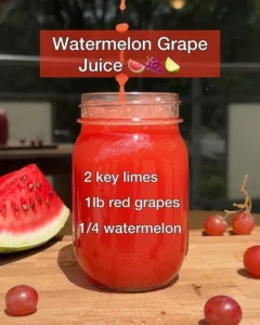 A refreshing glass of watermelon grape juice served with fresh fruit slices.