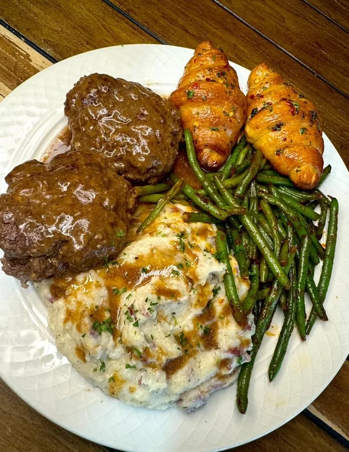 Delicious Salisbury steak dinner served with gravy and sides